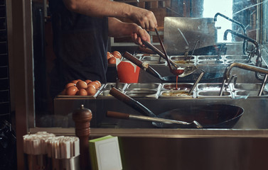 Cooking process in an Asian restaurant. Cook is stirring vegetables in wok.