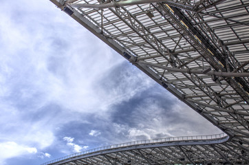 Stadium roof against the blue sky with white clouds.