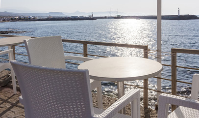 Tables with wooden chairs in traditional Greek tavern in Gouves town on coast of Crete island, Greece