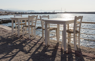 Greek tavern with orange wooden chairs by sea coast, Greece, Santorini island in Cyclades....