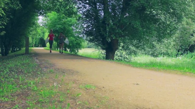 Two girls carrying trash while plogging outdoors