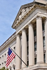 U.S. flag in front of Supreme Court building in Washington, D.C. with blue sky.