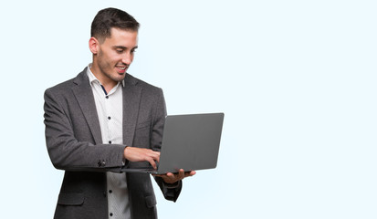 Handsome young man using computer laptop with a happy face standing and smiling with a confident smile showing teeth