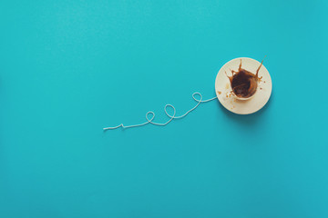 Coffee cup in shape of balloon with clouds on blue paper background. Toned