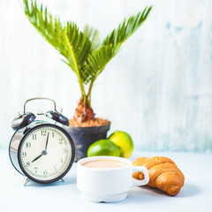 morning coffee in a white cup Croissant on a light background Wake-up with an alarm clock Breakfast cheerfulness, a healthy breakfast freshness Copy spase..