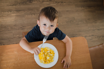 the child eagerly in the kitchen eating scrambled eggs, day, the view from the top