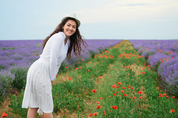 young girl is in the lavender field with red poppy flowers, beautiful summer landscape