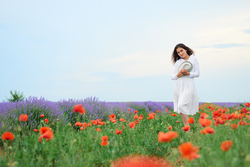Fototapeta na wymiar young girl is in the lavender field with red poppy flowers, beautiful summer landscape