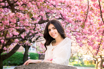 portrait of a young teenage girl looking at blooming sakura trees