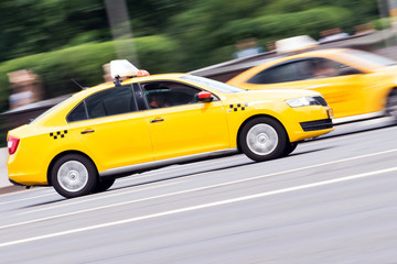 yellow taxi rides with great speed on the road, the effect of blur in the traffic