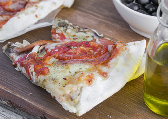 Pizza with chicken and tomatoes served on a wooden stand