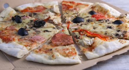 Pizza salami with olives is served on a wooden stand