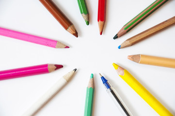 Multi-colored pencils for painting lie on a white background