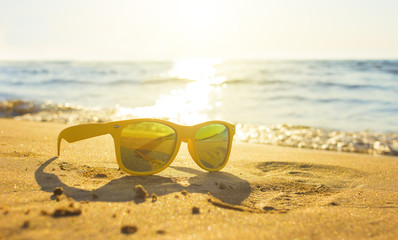 Yellow glasses the sea sand, sunglasses with beautiful sea scenery. sunglasses are reflected in the Golden wet sand as in the mirror