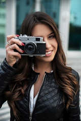 Young smiling woman taking photos with retro camera