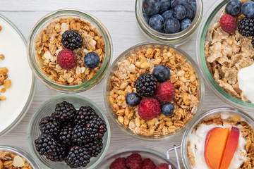 Jars full with granola, yogurt and fresh berries, top view, selective focus