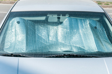 Fototapeta premium Sun reflector on the windscreen or windshield as protection of the car plastic indoor panel from direct sunlight and heat