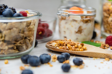 Jars full with granola, yogurt and fresh berries and wood spoon full whit granola, close-up, selective focus