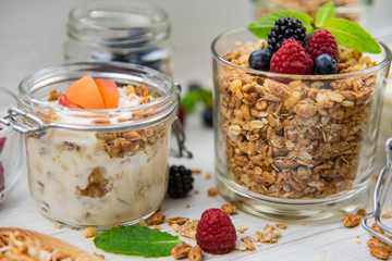 Jars full with granola, yogurt and fresh berries and wood spoon full whit granola, close-up, selective focus