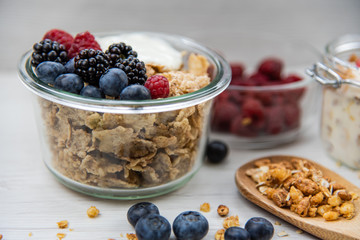 Jars full with granola, yogurt and fresh berries and wood spoon full whit granola, close-up, selective focus