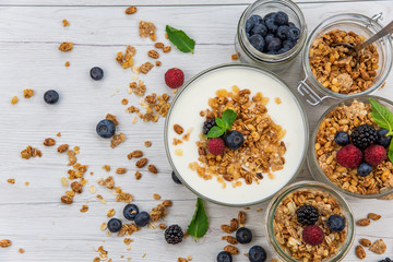 Jars full with granola, yogurt and fresh berries, top view, selective focus