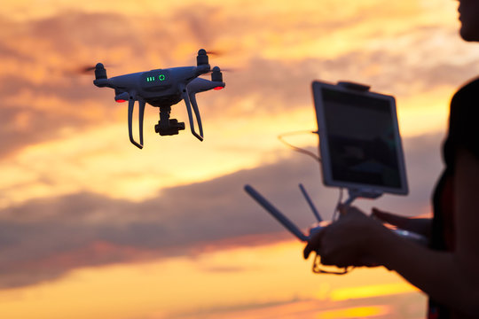 drone quadcopter with digital camera flying at sunset