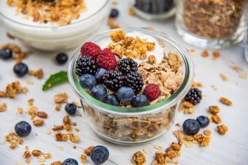 Jars full with granola, yogurt and fresh berries, close-up, selective focus