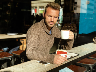 Man drinking a coffee and eating a cake