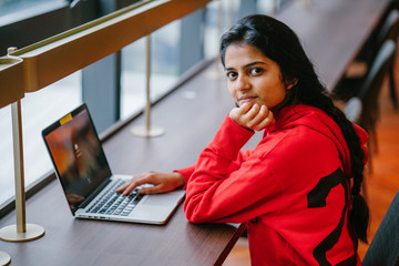 A successful youthful Indian woman looking up from a laptop and smiling