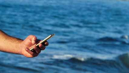 Male hand using smartphone on the beach