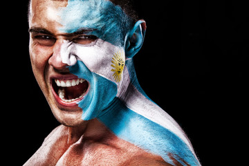 Soccer or football fan with bodyart on face with agression - flag of Argentina.