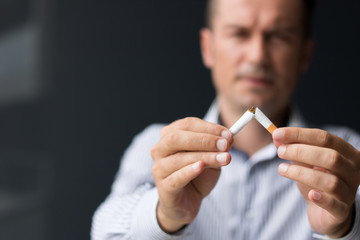 Quitting smoking habit. Stop smoking concept. Close-up of man breaks cigarette in half.