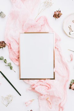 Photo frame with copy space on pink blanket with eucalyptus branches and rose flowers on white background. Flat lay, top view still life artist concept.