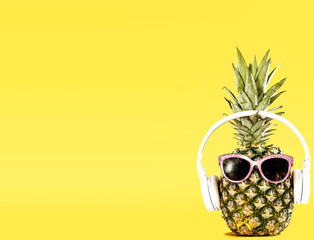 Funny Pineapple with Sunglasses and Headphones on Yellow Background – Summer Vibes. Copy space...