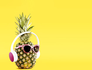Funny Pineapple with Sunglasses and Headphones on Yellow Background – Summer Vibes. Copy space...