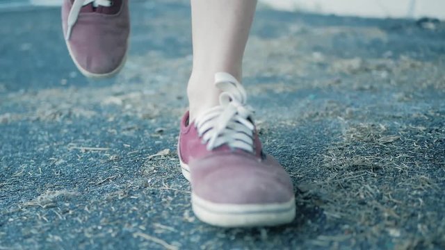 the girl kicks dirt or trash on the road. focus on legs in red sneakers