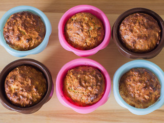 Healthy muffins from whole-grain cereals and oat flakes with poppy close-up in multi-colored baking molds and a wooden board.