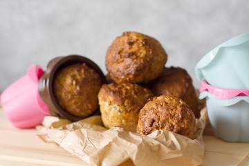 Healthy muffins from whole-grain cereals and oat flakes with poppy close-up against a background of baking molds and a wooden board.