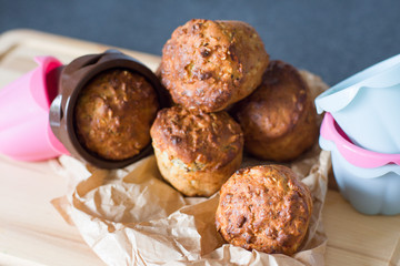 Healthy muffins from whole-grain cereals and oat flakes with poppy close-up against a background of baking molds and a wooden board.