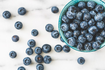 Top view of a blue bowl with fresh ripe blueberry over white background. The concept of healthy eating and lifestyle.