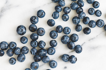 Fresh ripe blueberries over white marble. Food background. The concept of healthy eating and lifestyle.