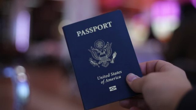 A blue American passport in hand