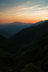 Sunset high in the mountains. Peaks of high mountains and golden clouds in the sky. Evening landscape.