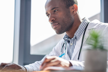 Cheerful African student being deep in thoughts