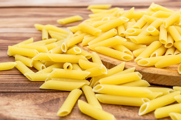 Cutting board with raw pasta on wooden table. Close up.