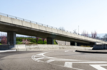 Modern curvy multilevel asphalt and concrete road intersection in morning sun
