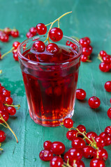 Red currant juice in glass with fruits on wood table