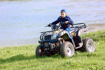 The boy is traveling on an ATV.