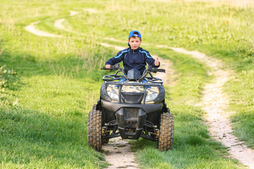 The boy skates on a quad bike in a beautiful area.