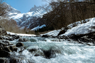 Fototapeta premium Mountain cold ice creek stream flowing rapidly in high mountains covered with stone